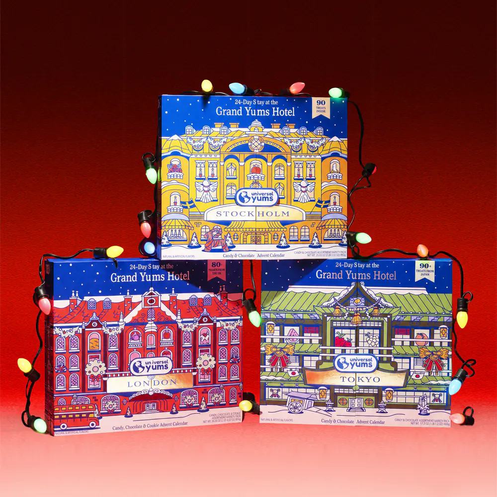 The Grand Yums Hotel Stockholm, London and Tokyo advent calendars stacked in a pyramid, wrapped in colored holiday lights.