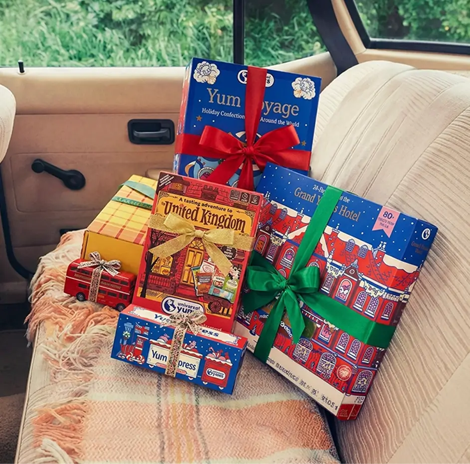 Wrapped Universal Yums holiday gift boxes stacked on the back seat of a car.