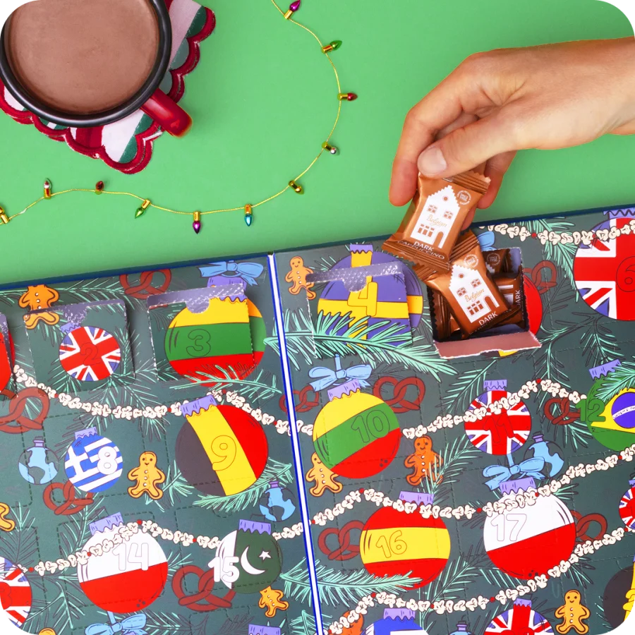 A hand opening a door of the Around The World Candy Advent Calendar and taking out two candies.